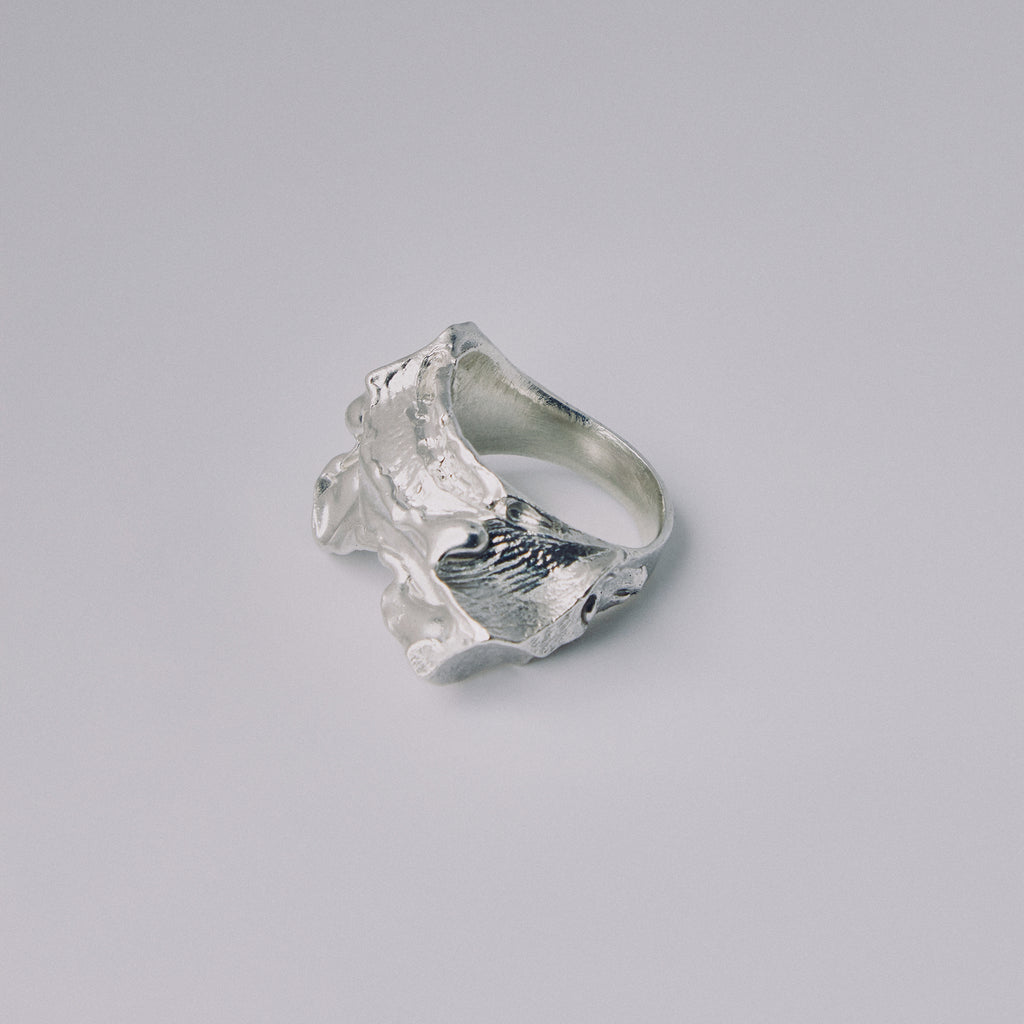 Silver ring with a textured design on a gray background