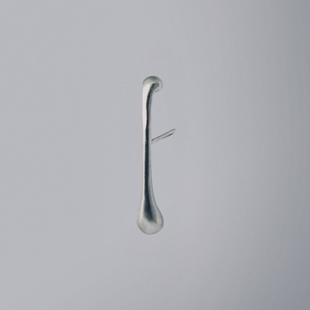 Silver earring on a light gray background