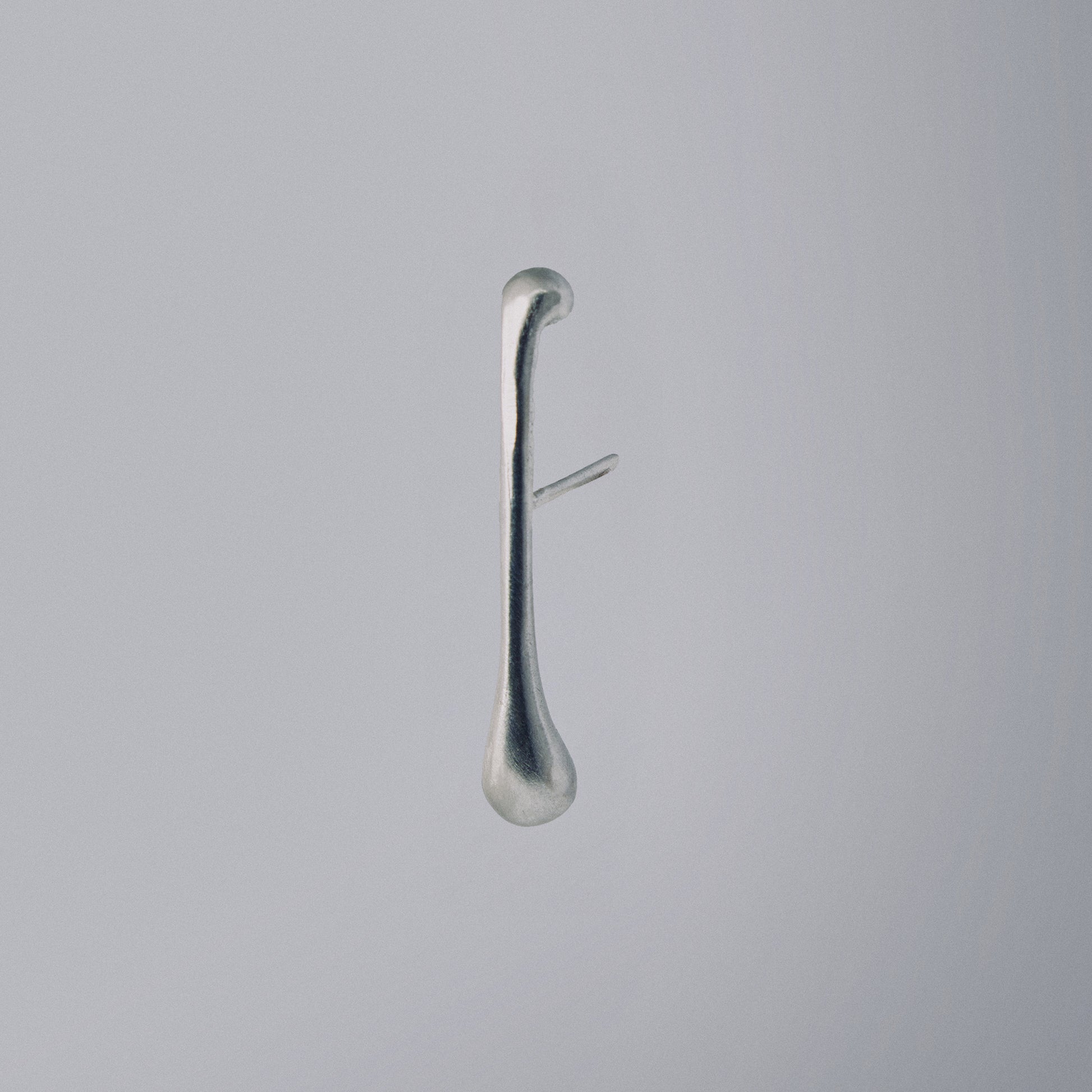 Silver earring on a light gray background