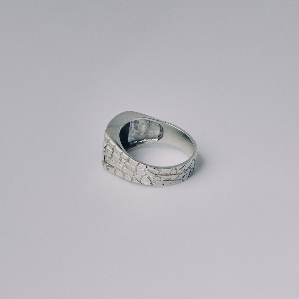 Silver ring with textured surface on a gray background