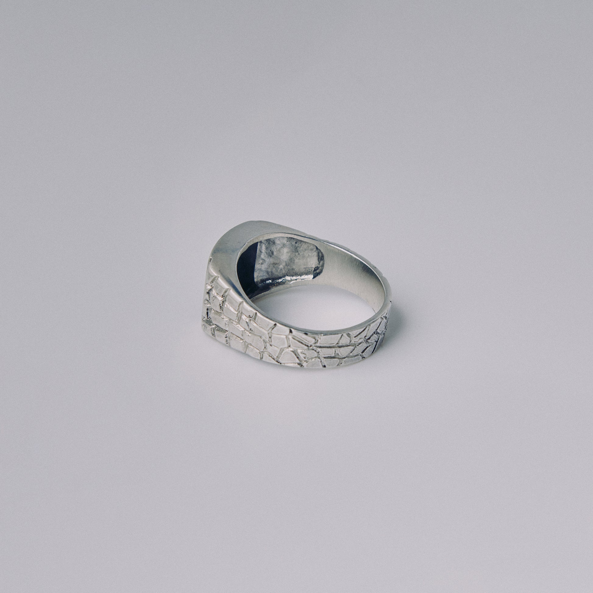 Silver ring with textured surface on a gray background