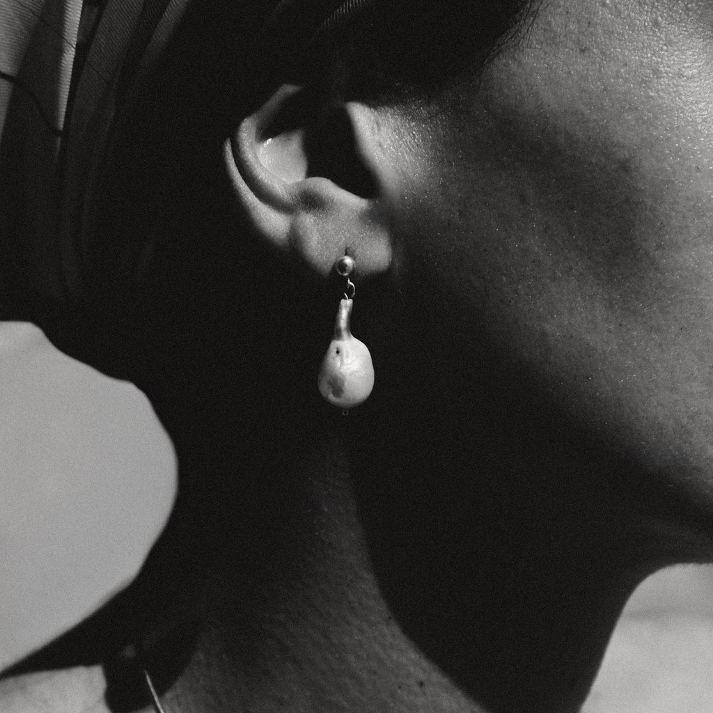 Close-up of an ear wearing a pearl earring with a blurred background
