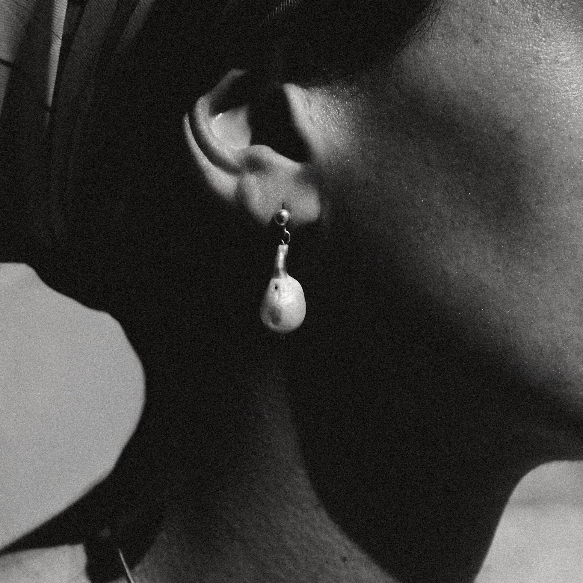 Close-up of an ear wearing a pearl earring with a blurred background