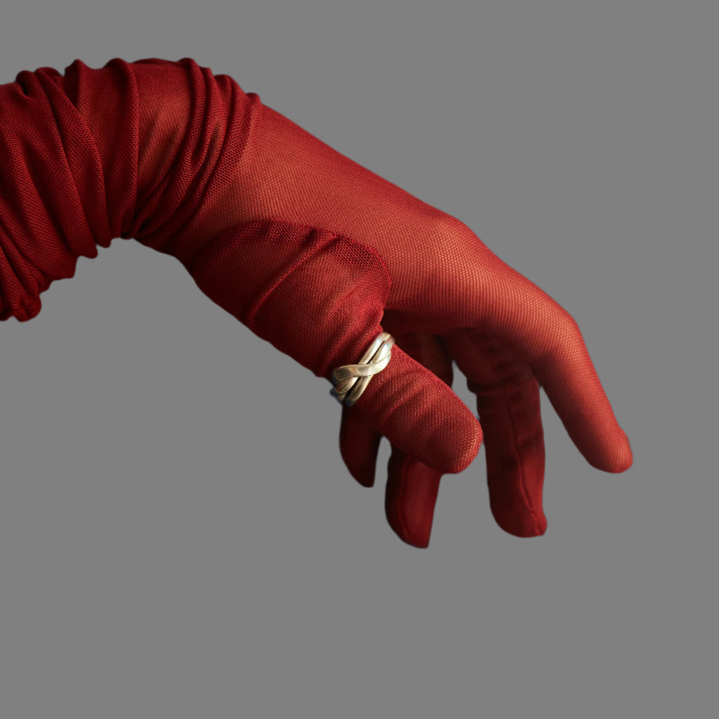 Red glove holding a gold ring against a blue curtain