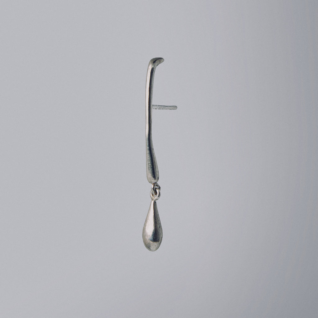 Silver earring with a teardrop design on a gray background