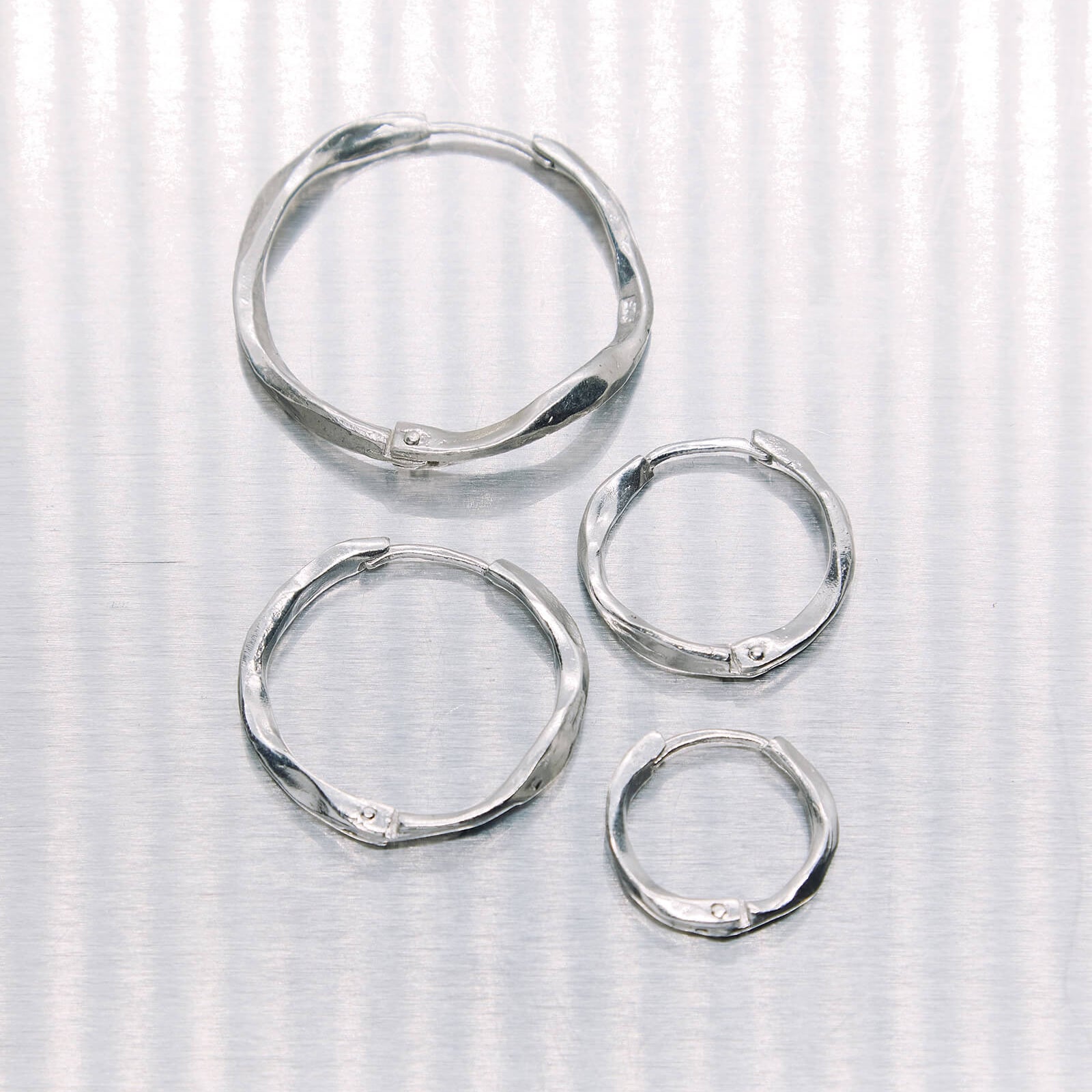 Set of silver hoop earrings on a textured white background