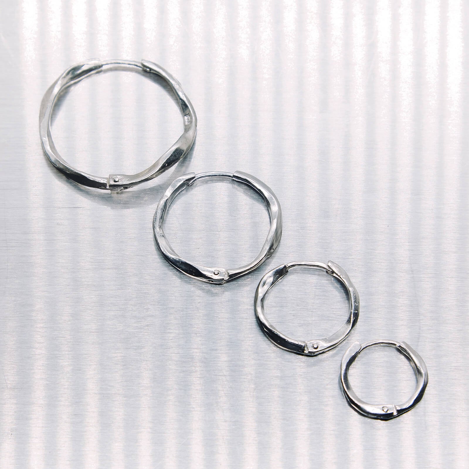 Set of silver hoop earrings on a textured white background