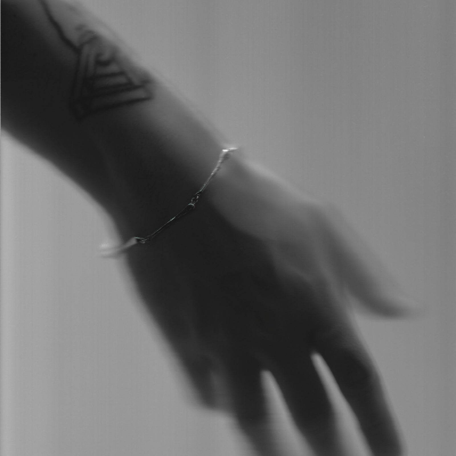 Hand wearing a silver bracelet with a blurred background