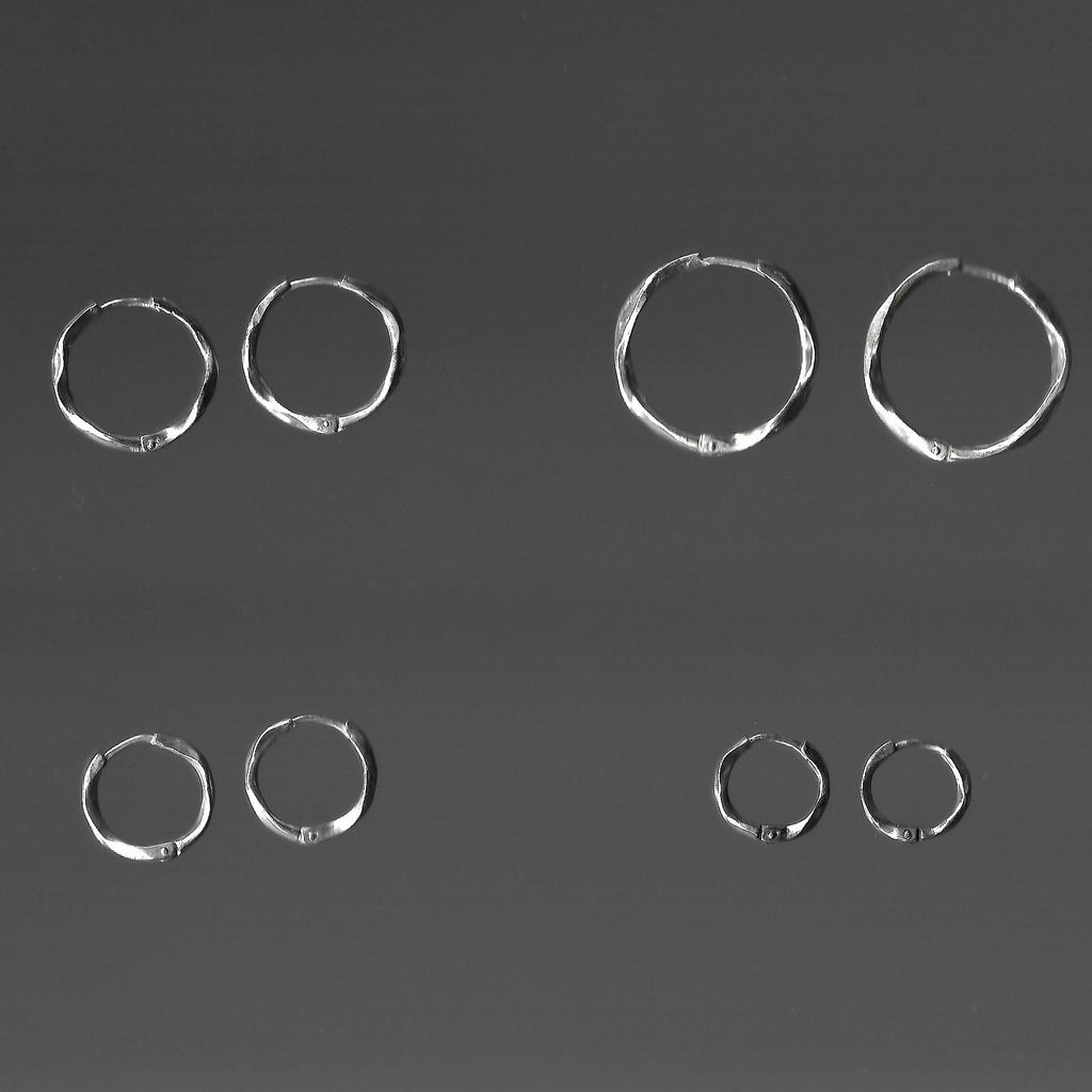 Set of silver hoop earrings on a dark gray background