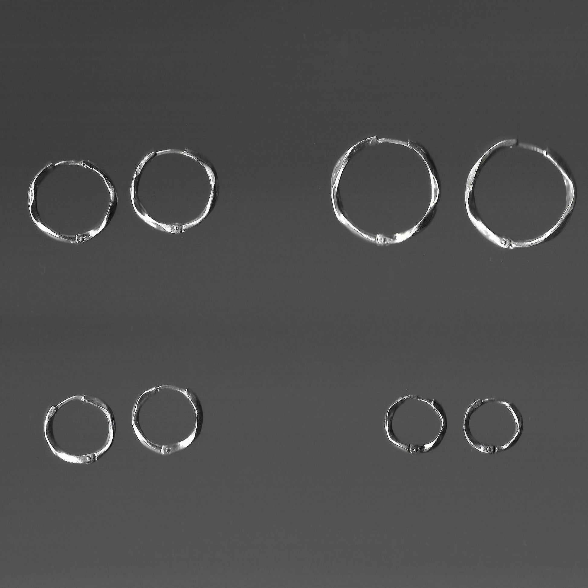 Set of silver hoop earrings on a dark gray background
