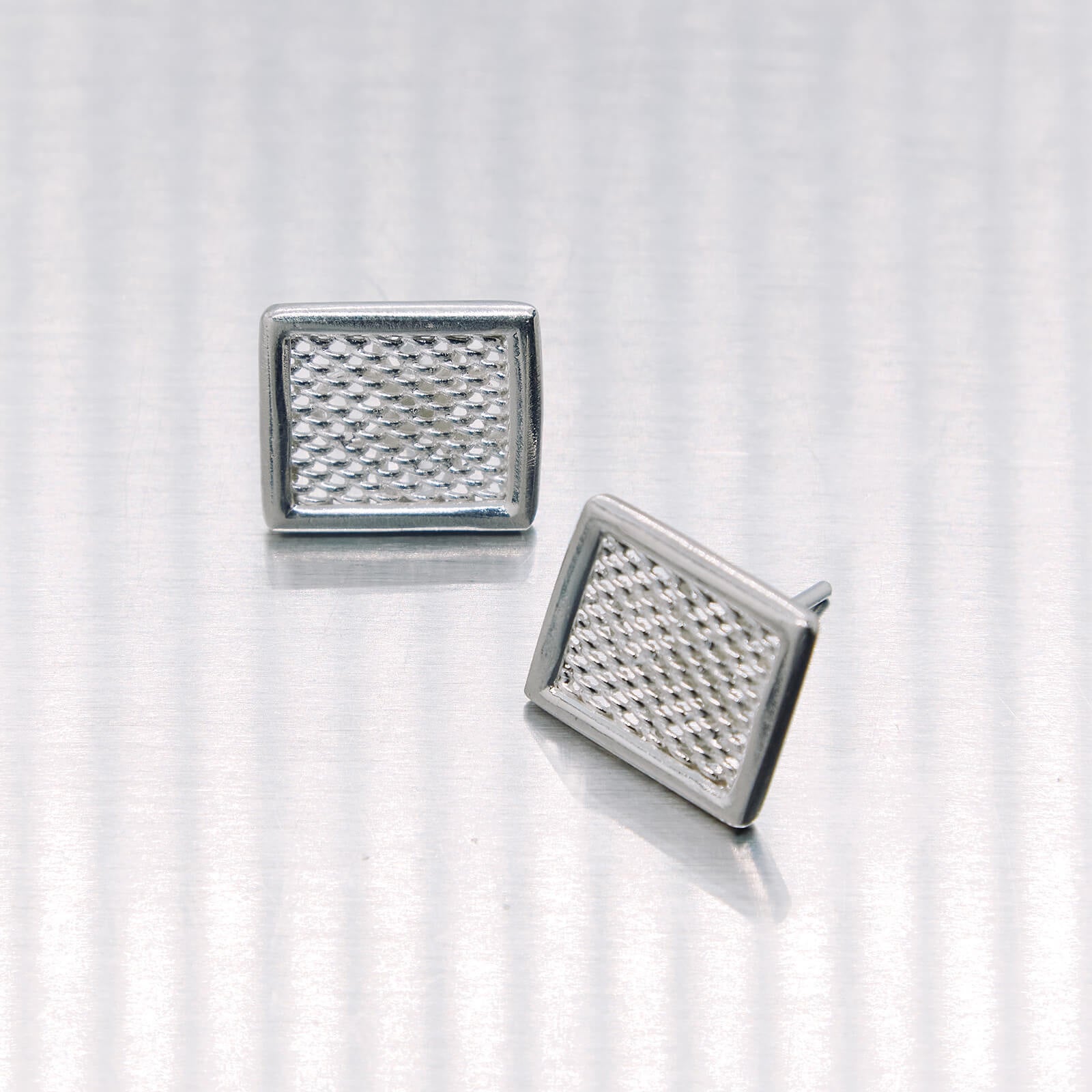 Pair of square silver earrings on a white background