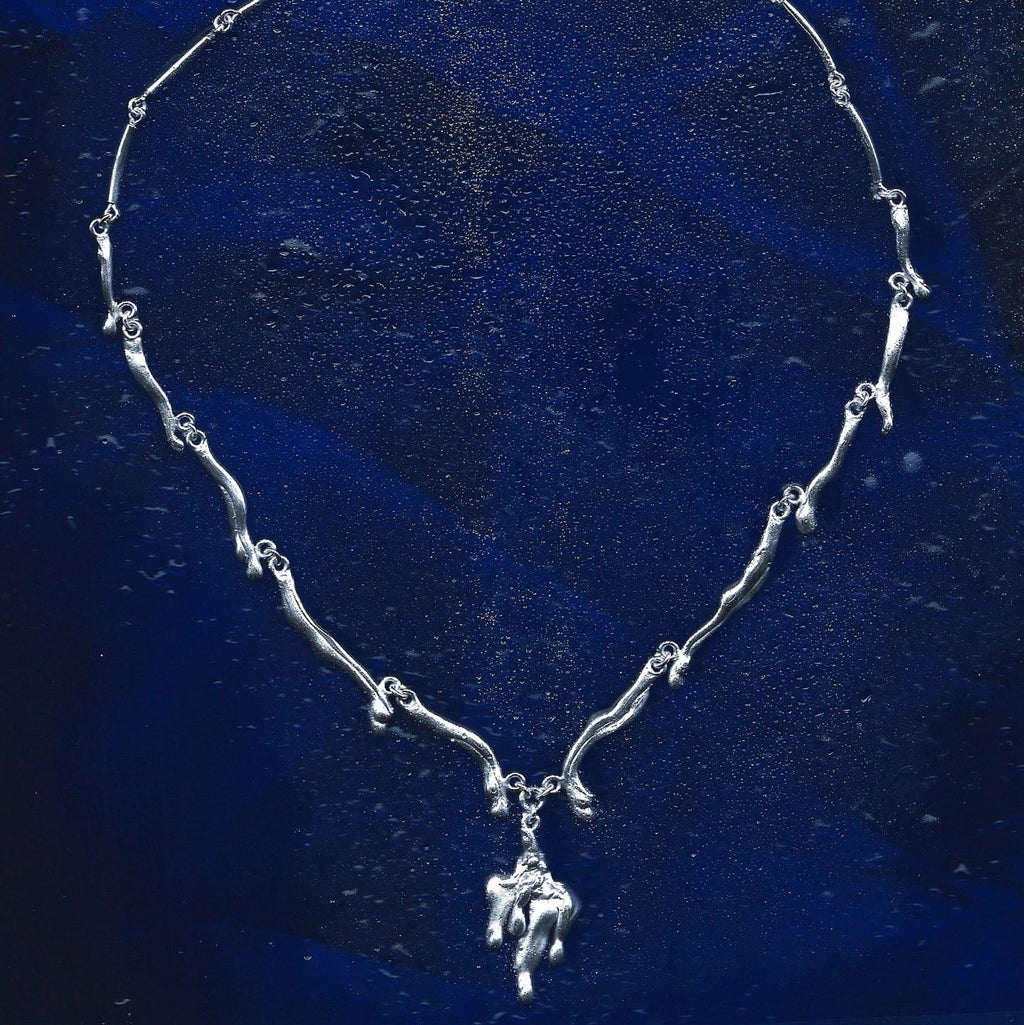 Silver necklace with a pendant on a blue textured background