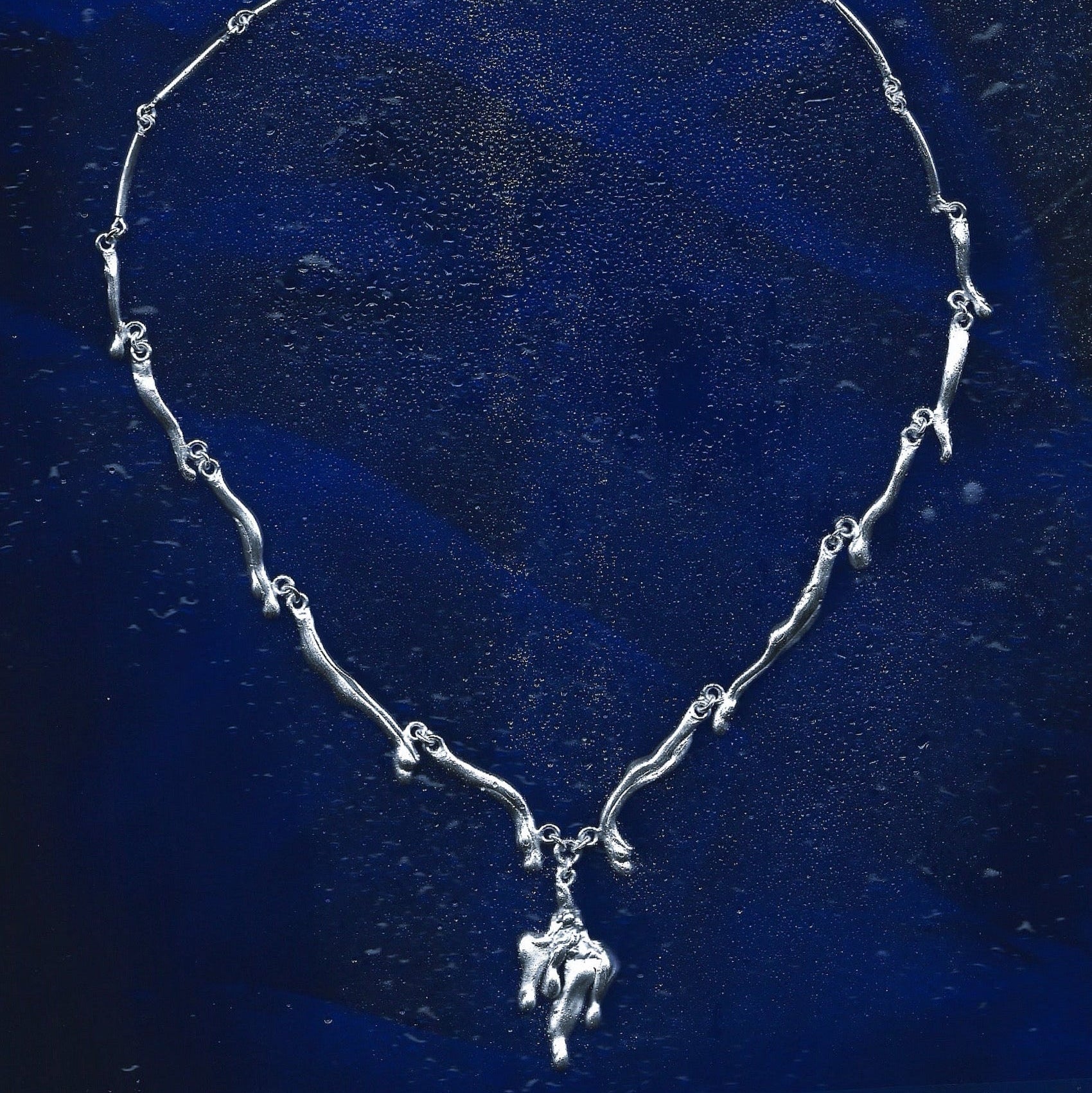 Silver necklace with a pendant on a blue textured background