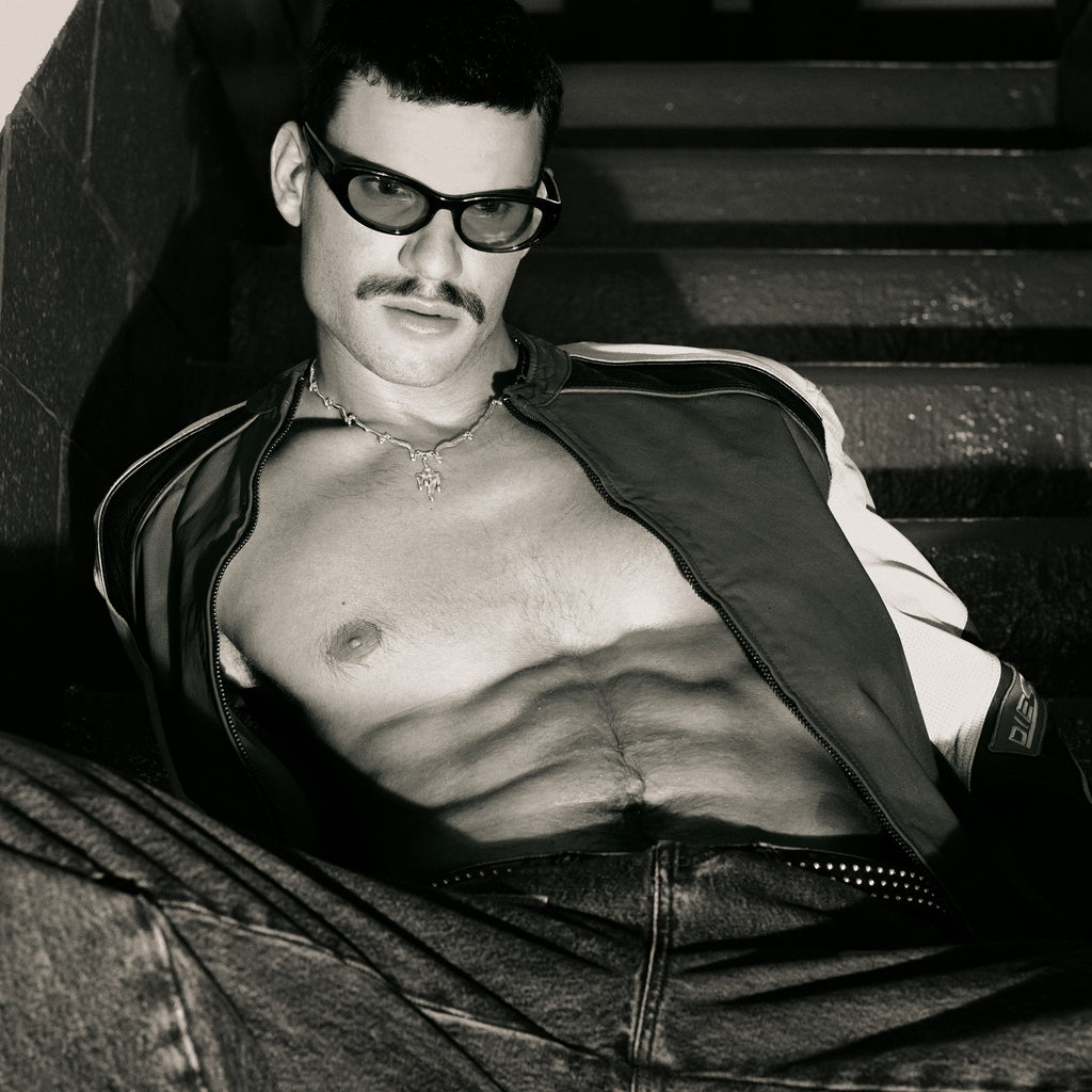 Man with sunglasses and a jacket sitting on steps