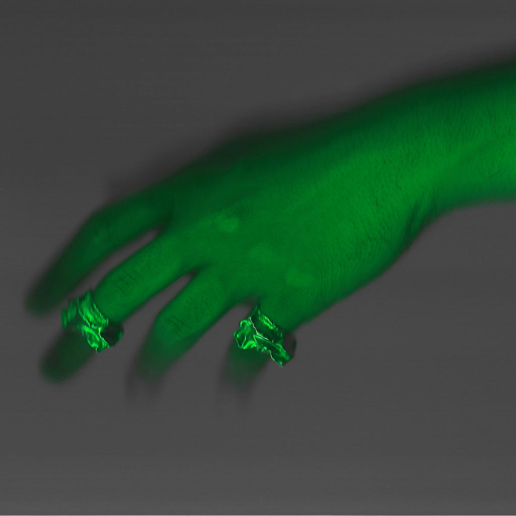 Hand with glowing green nail polish on a dark background
