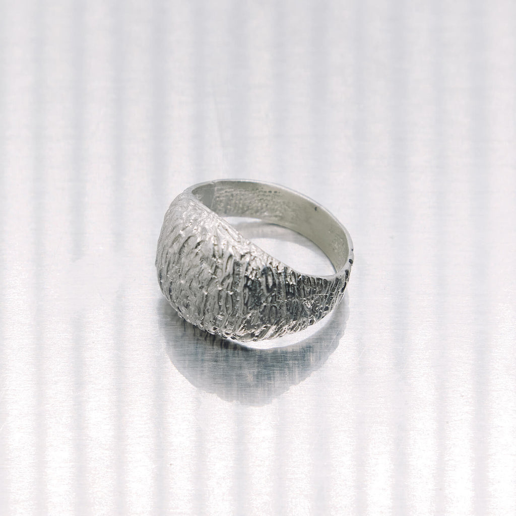 Silver ring with textured surface on a white background
