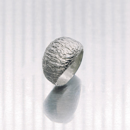 Silver ring with textured surface on a white background
