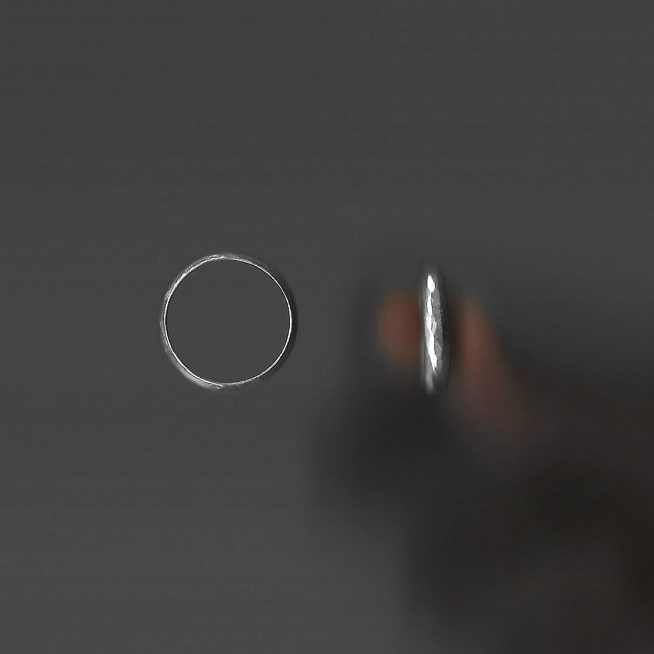 Two silver rings on a dark gray background
