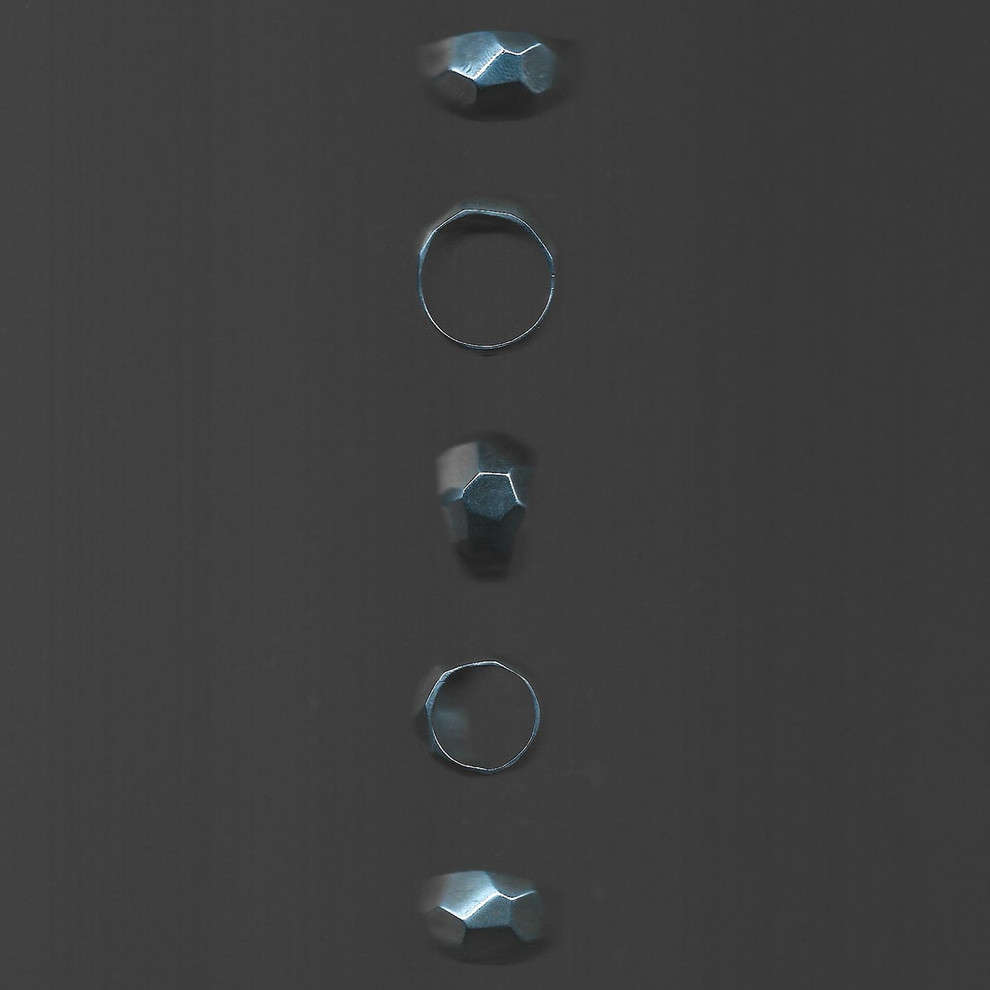 Five metallic rings of different sizes on a dark gray background