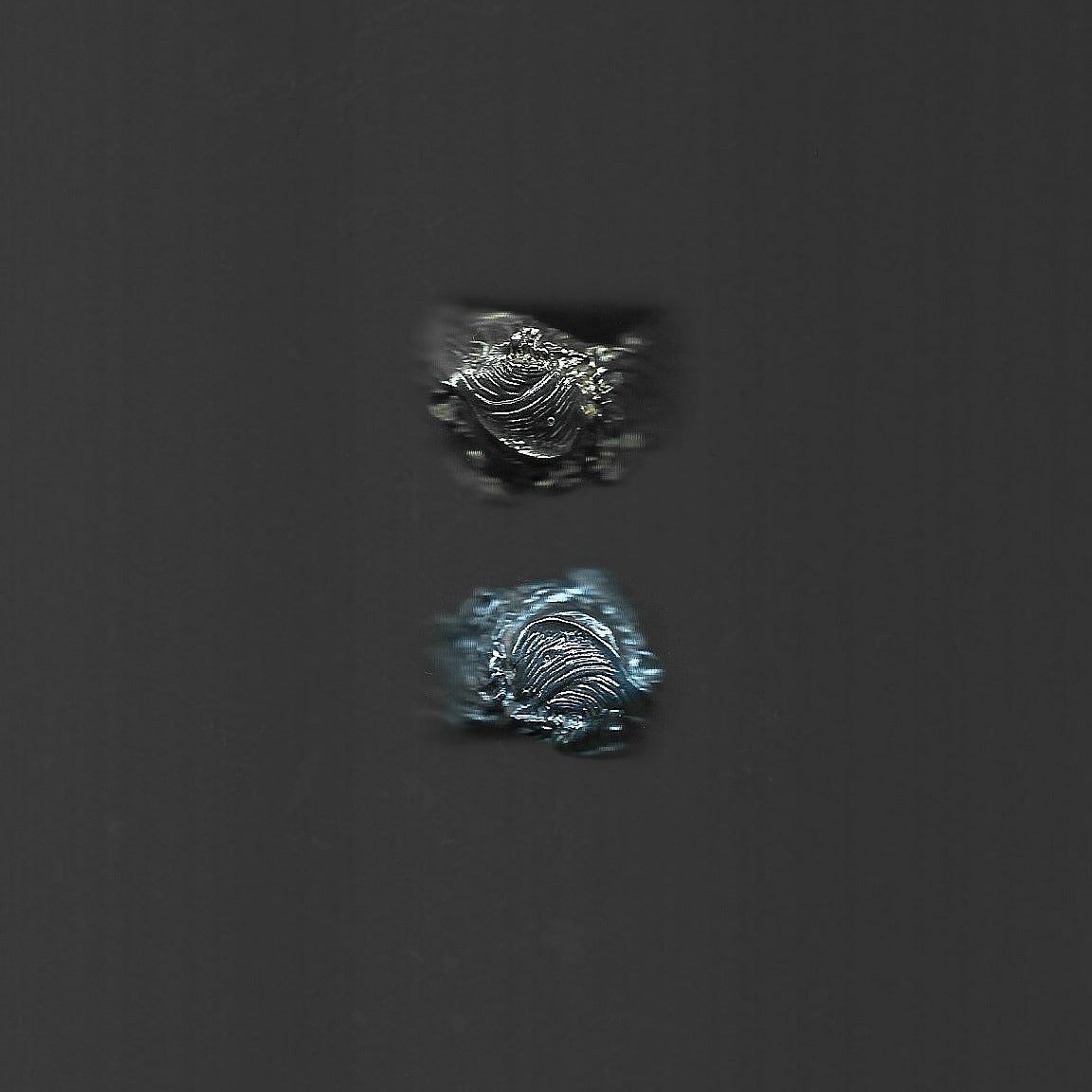 Two metallic objects on a dark gray background
