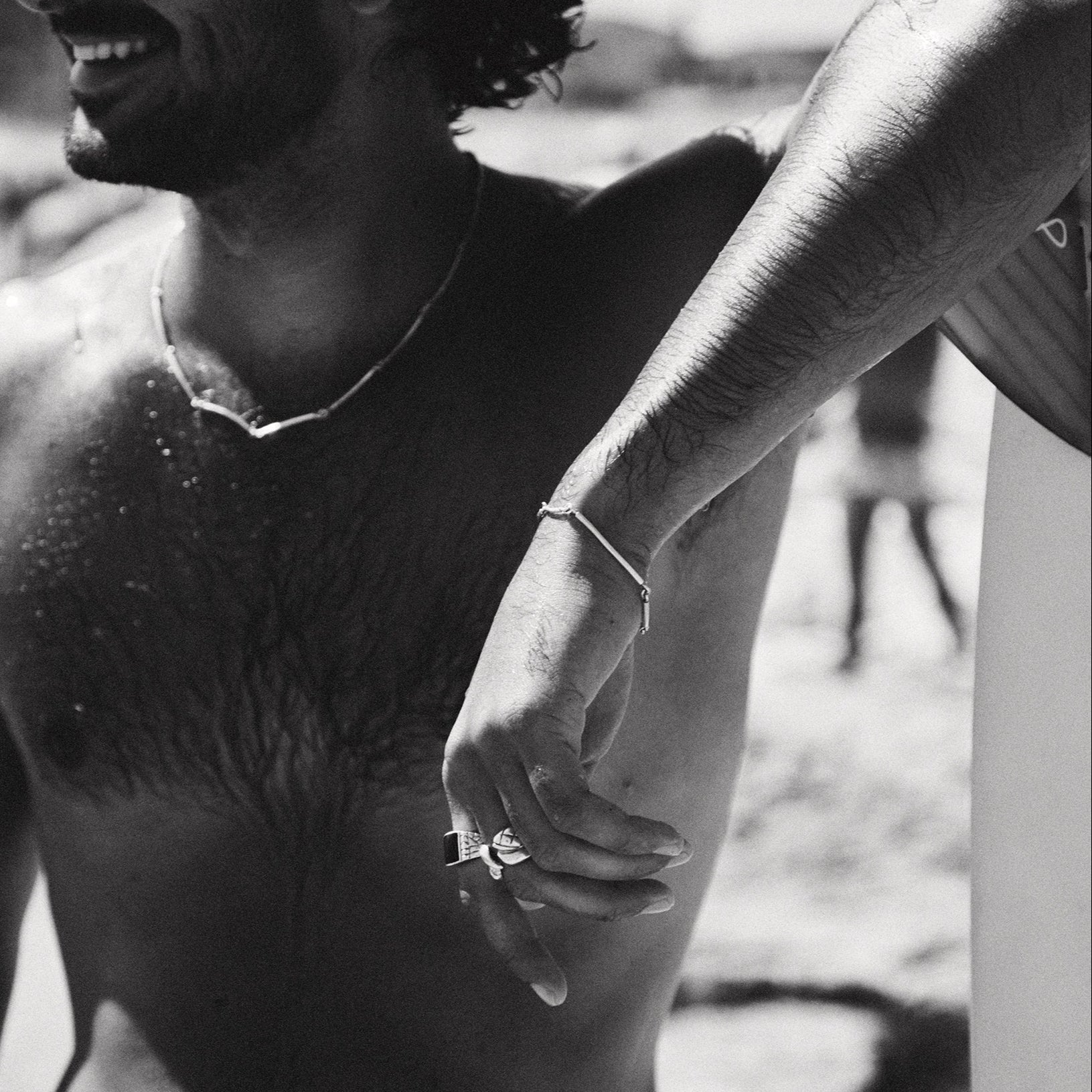 Black and white photo of a shirtless man with sunglasses on a beach.