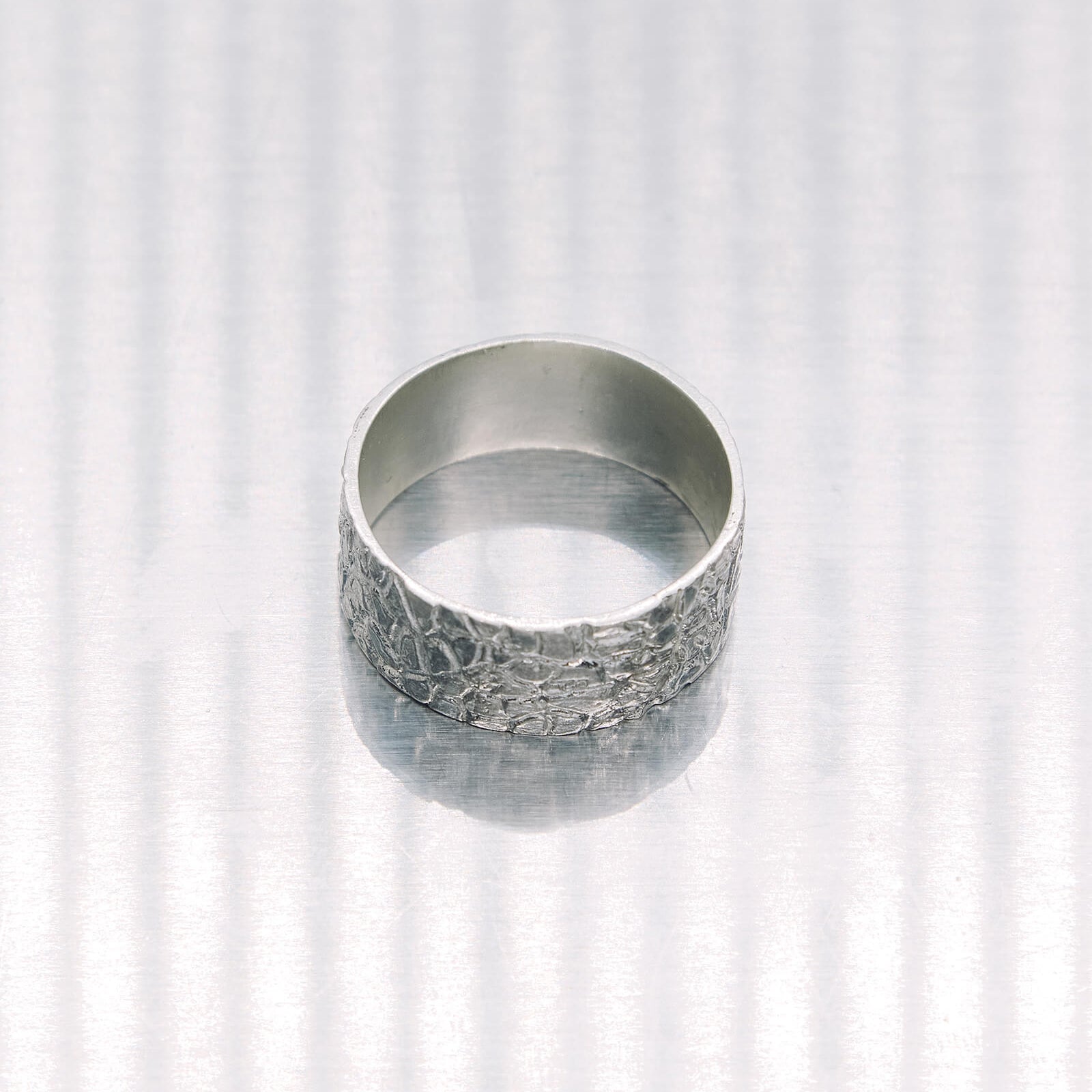 Silver textured ring on a white background