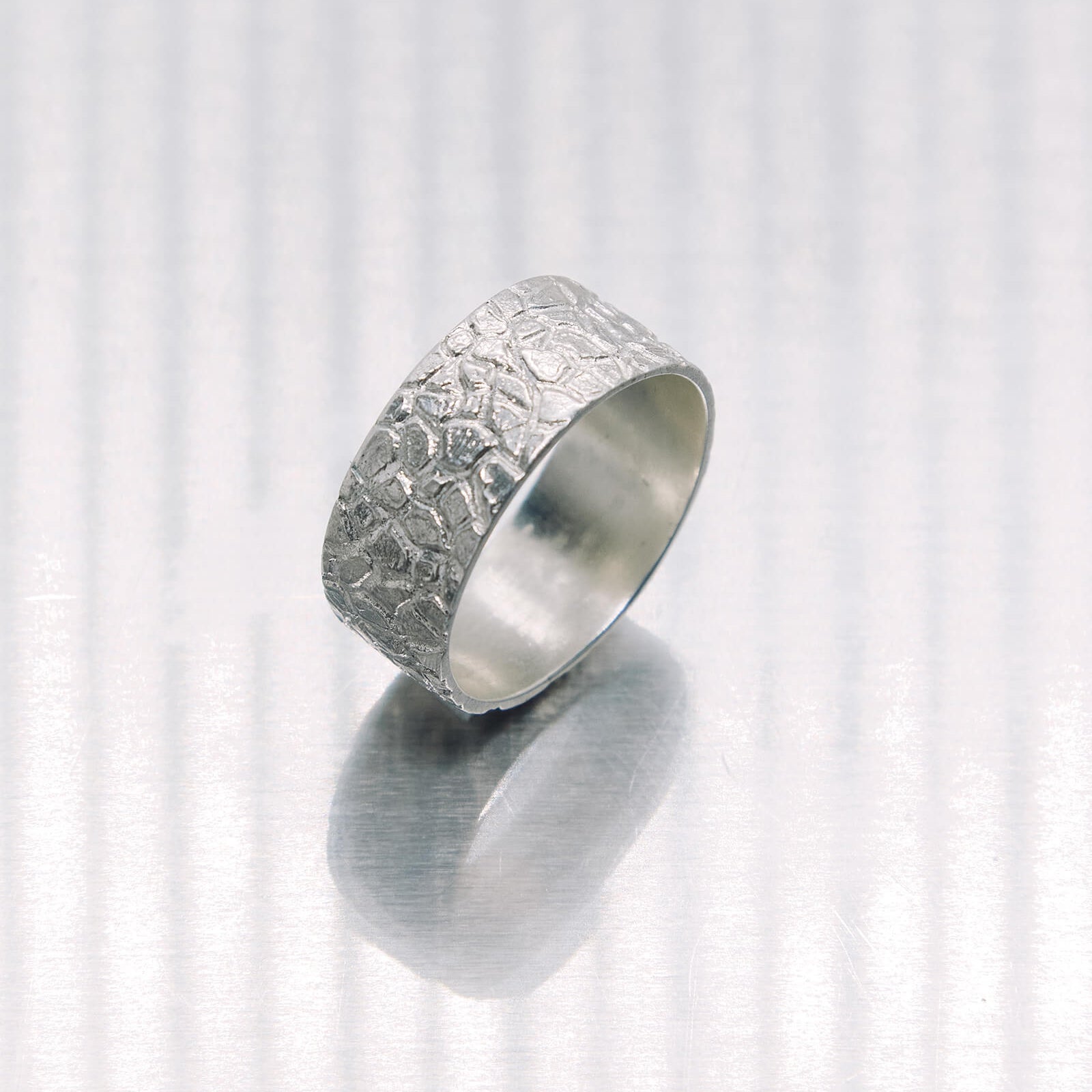 Silver ring with textured surface on a white background