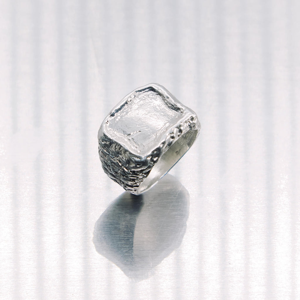 Silver ring with a textured band on a white background