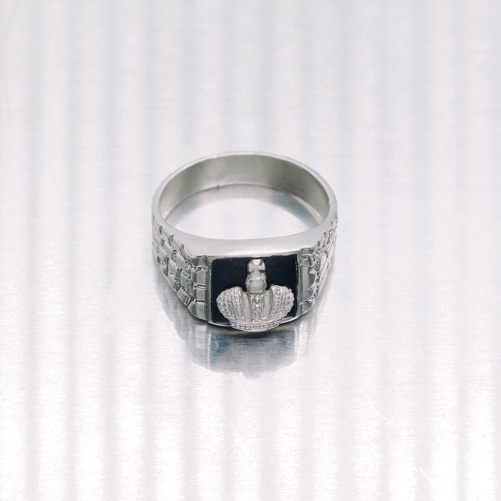 Silver ring with a black center and emblem on a white background