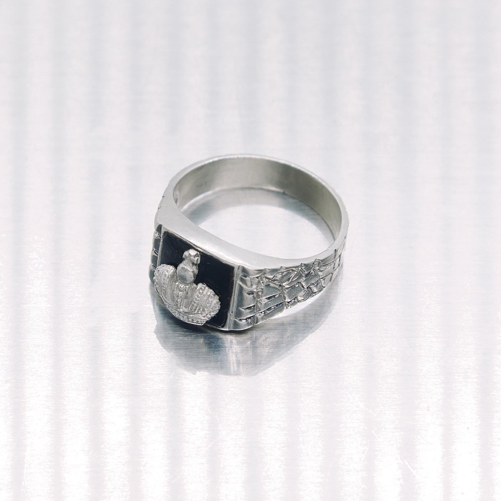 Silver ring with a crown design on a white background