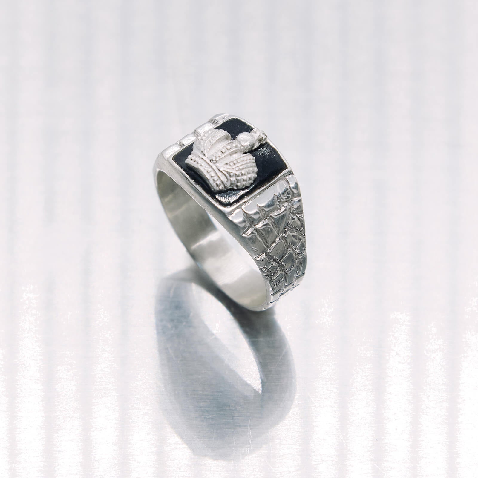 Silver ring with intricate design on a white background