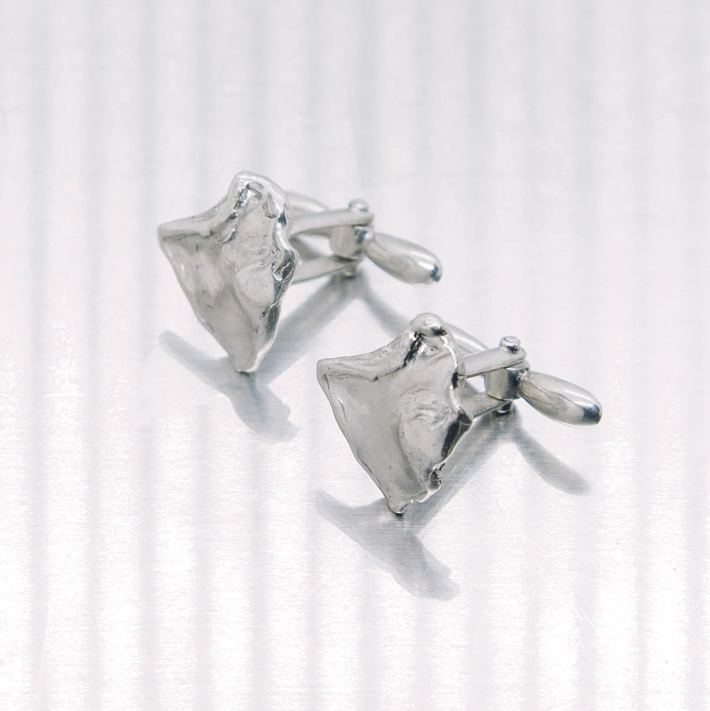 Pair of silver shark tooth cufflinks on a white background