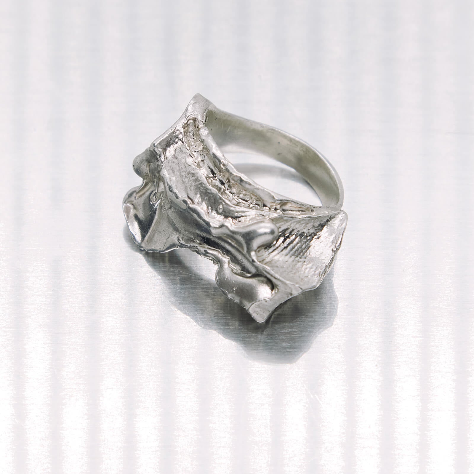 Silver ring with a textured design on a white background