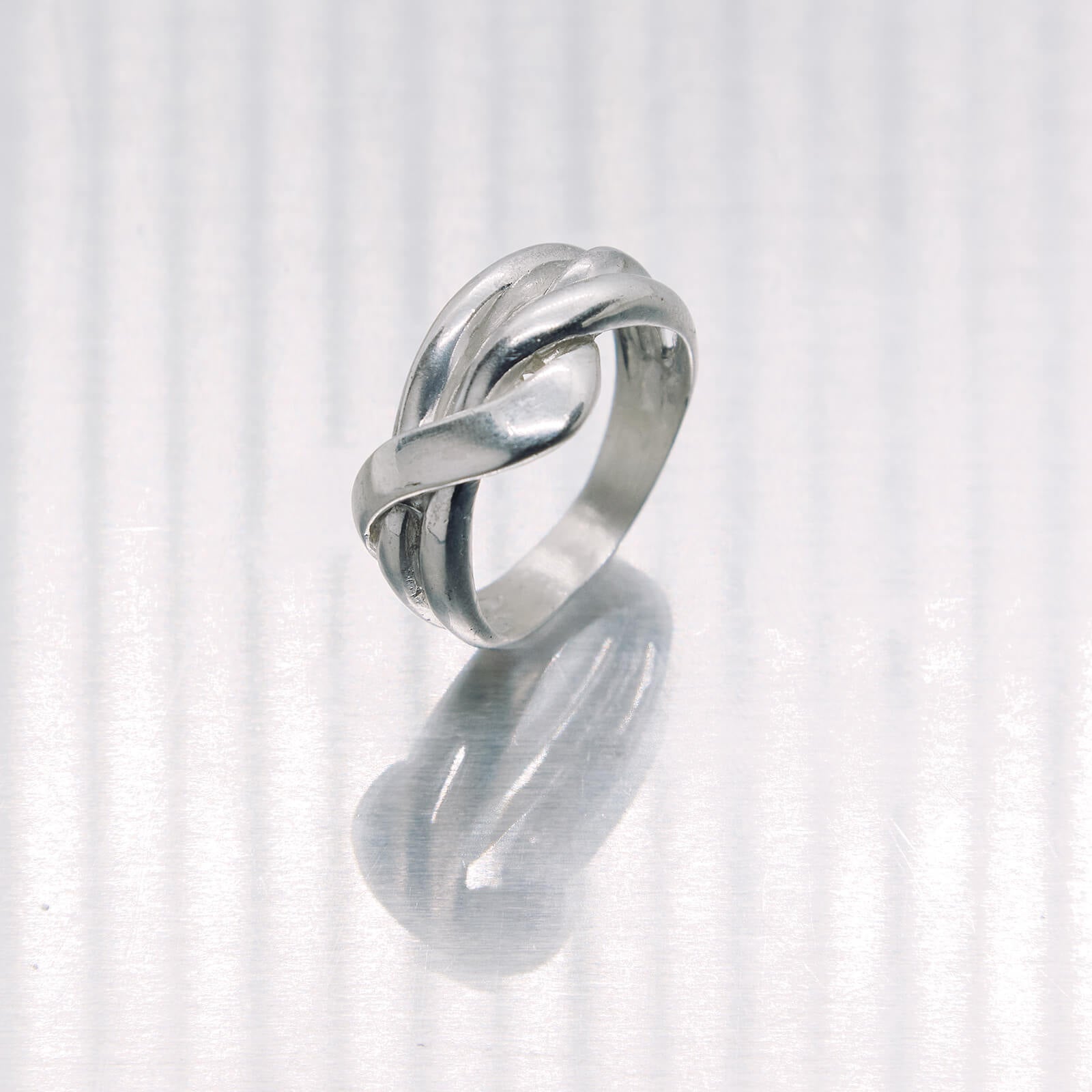 Silver ring with a knot design on a white background