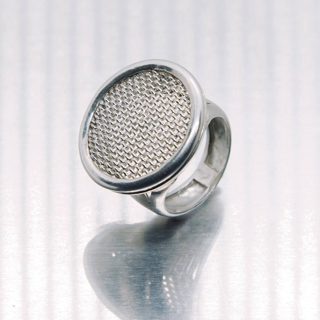Silver ring with textured design on a white background