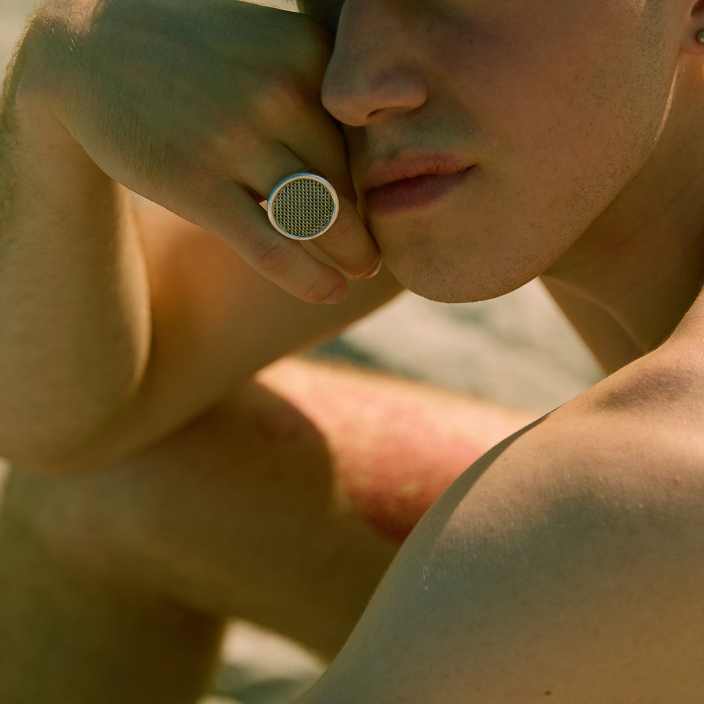 Person wearing a ring with a textured design on a blurred background
