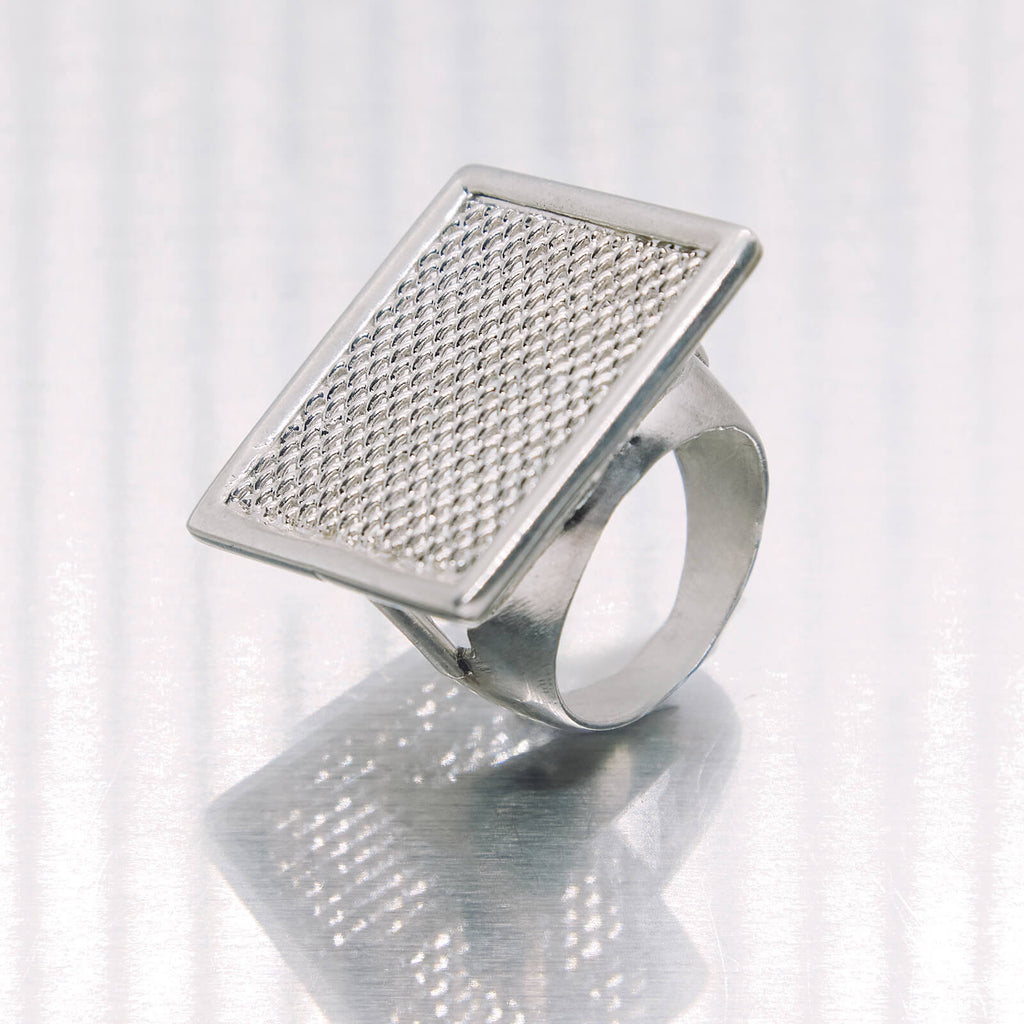 Silver ring with textured square design on a white background
