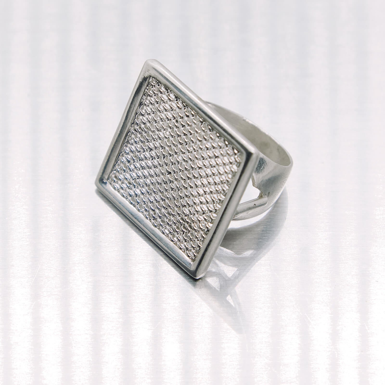 Silver ring with textured design on a white background