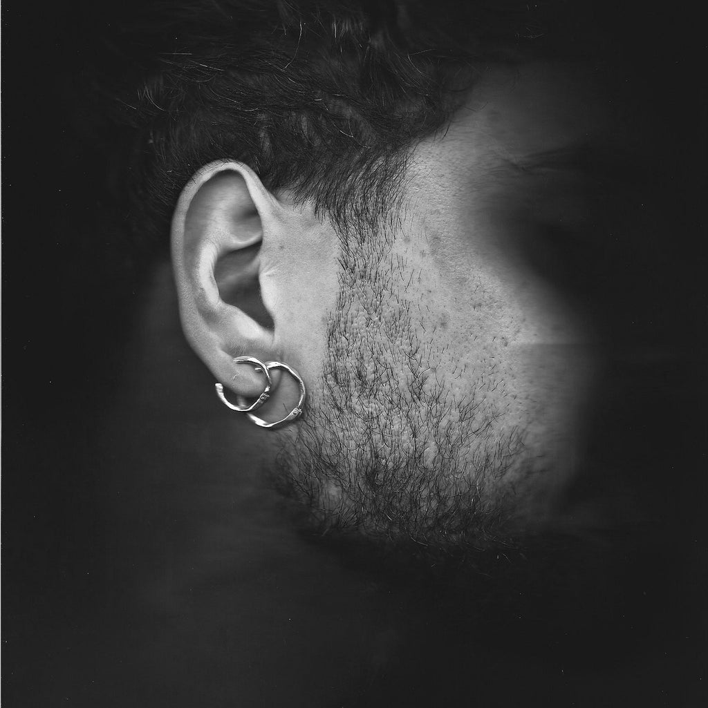 Close-up of an ear with a unique earring against a dark background