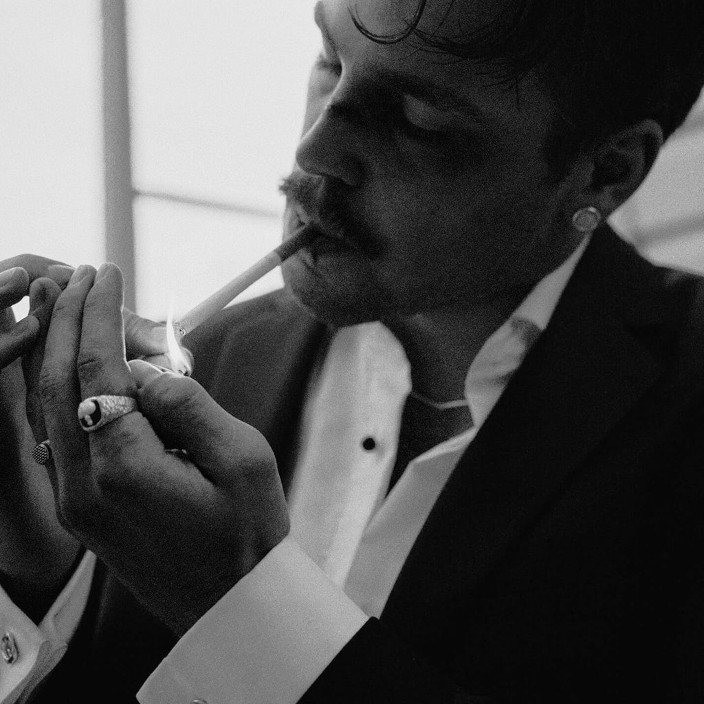 Man in formal attire lighting a cigarette with a blurred background