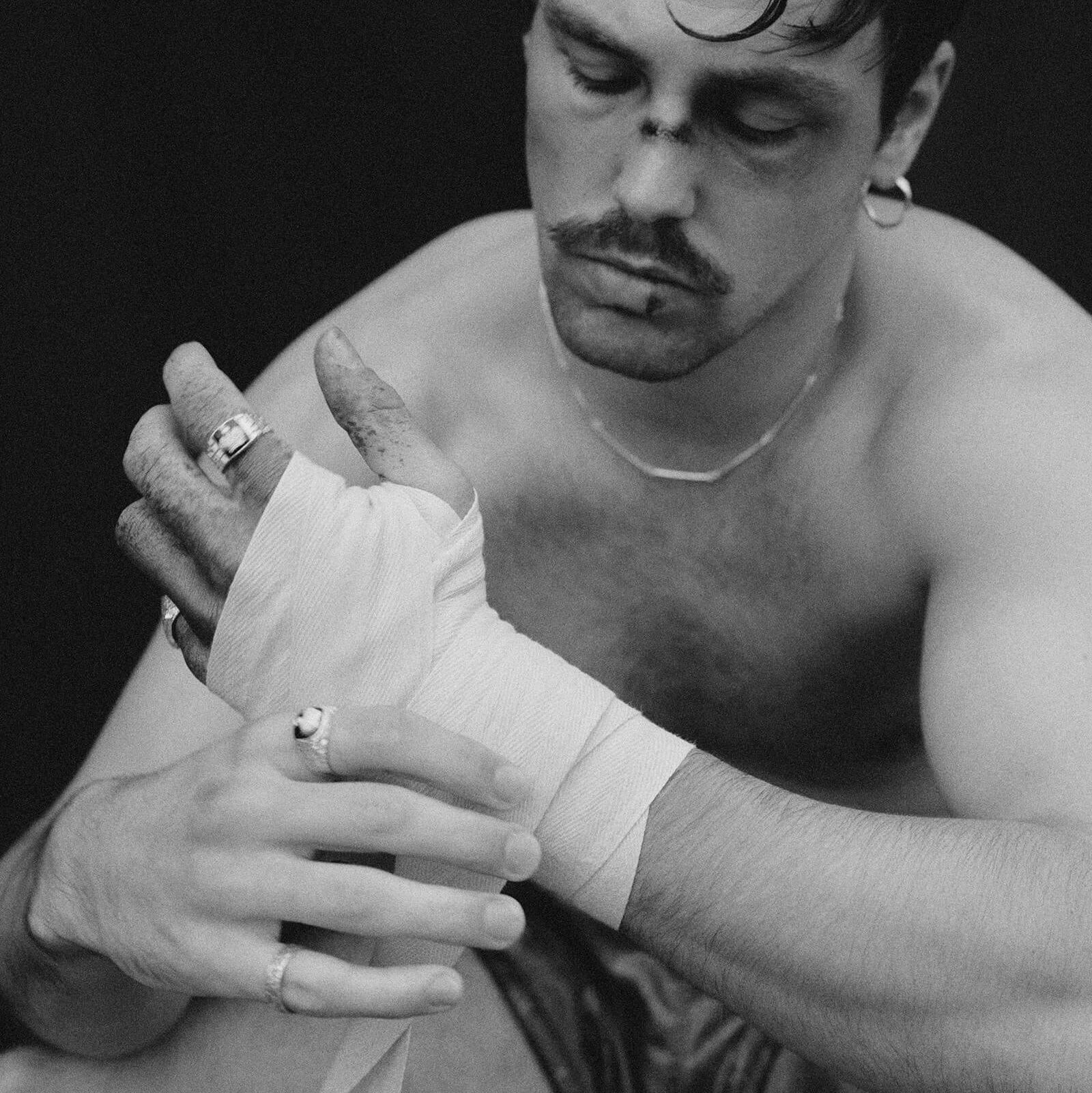Black and white photo of a boxer wrapping his hands.