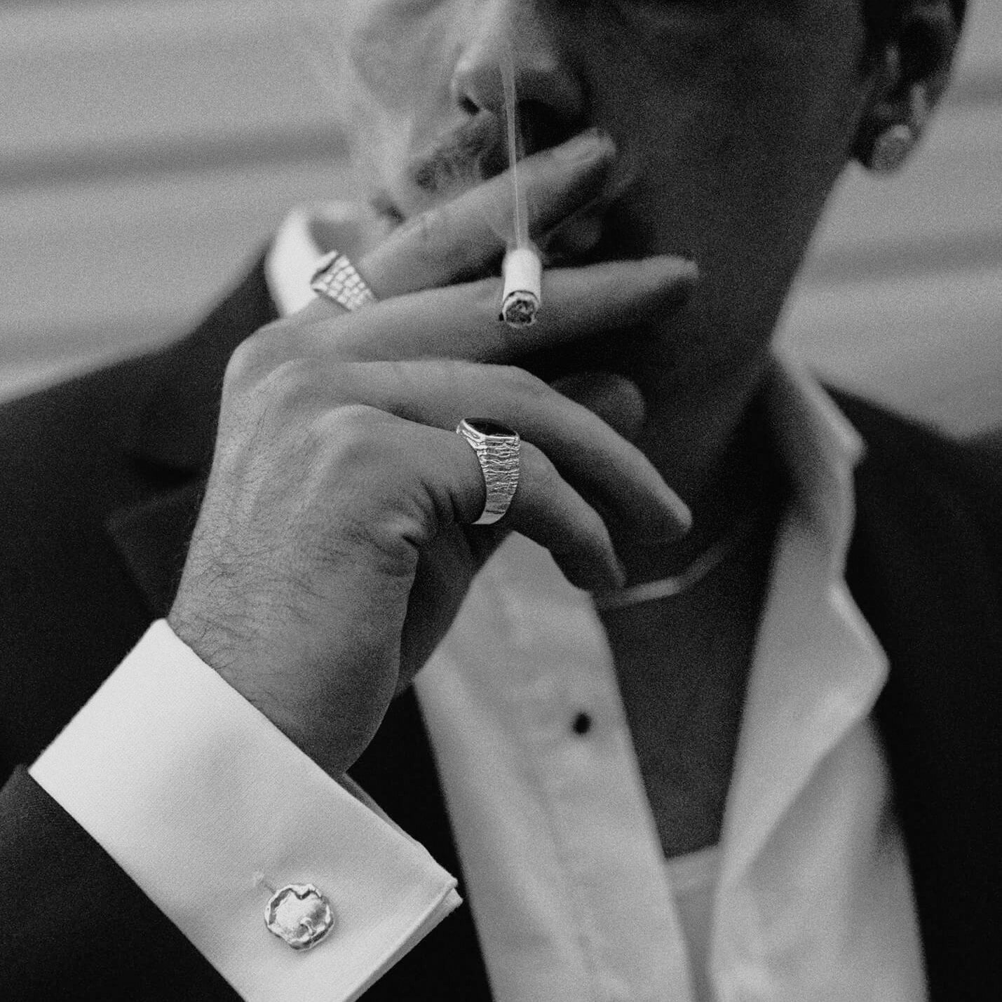 A man smoking a cigarette with a silver rings