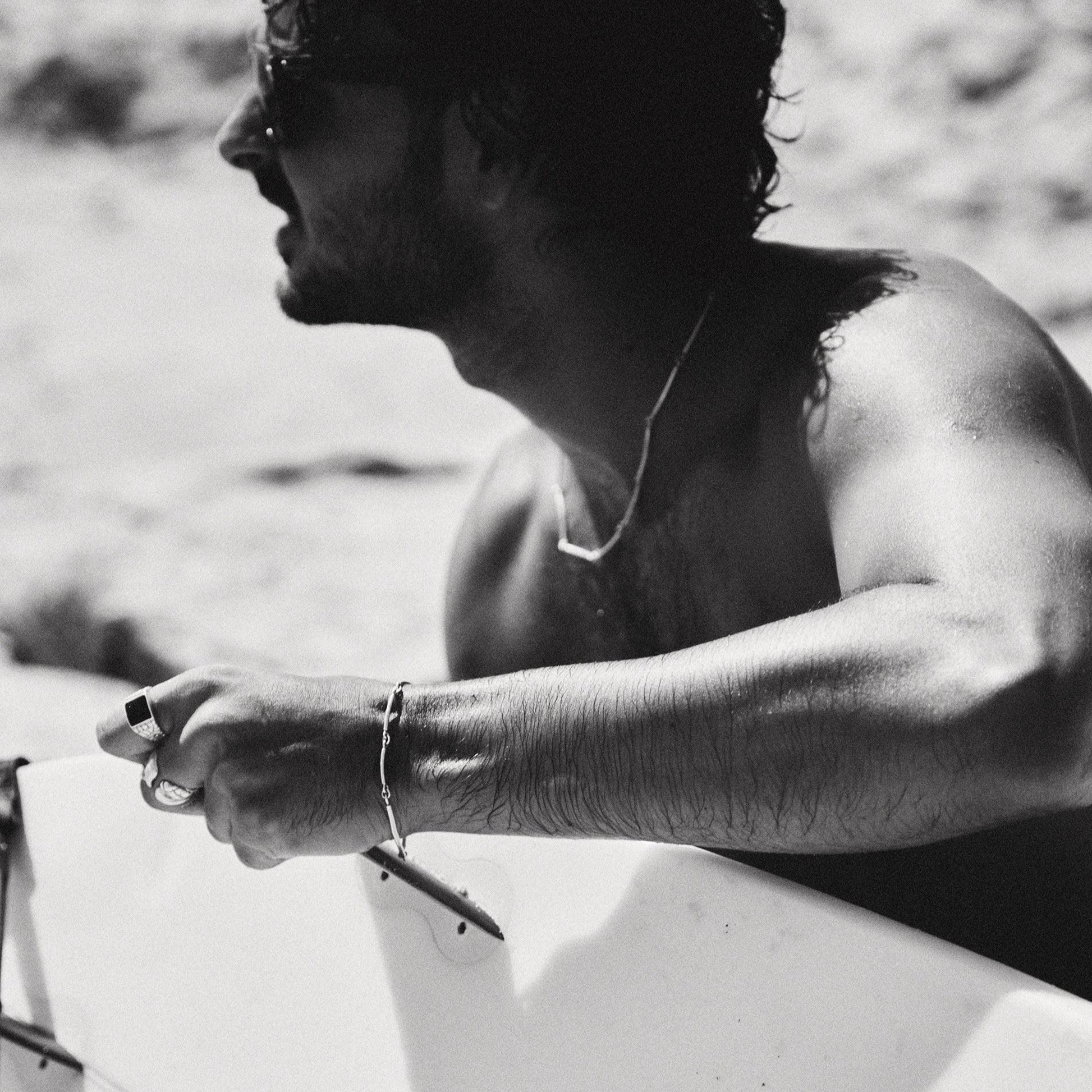 Black and white photo of a person holding a surfboard on a beach.