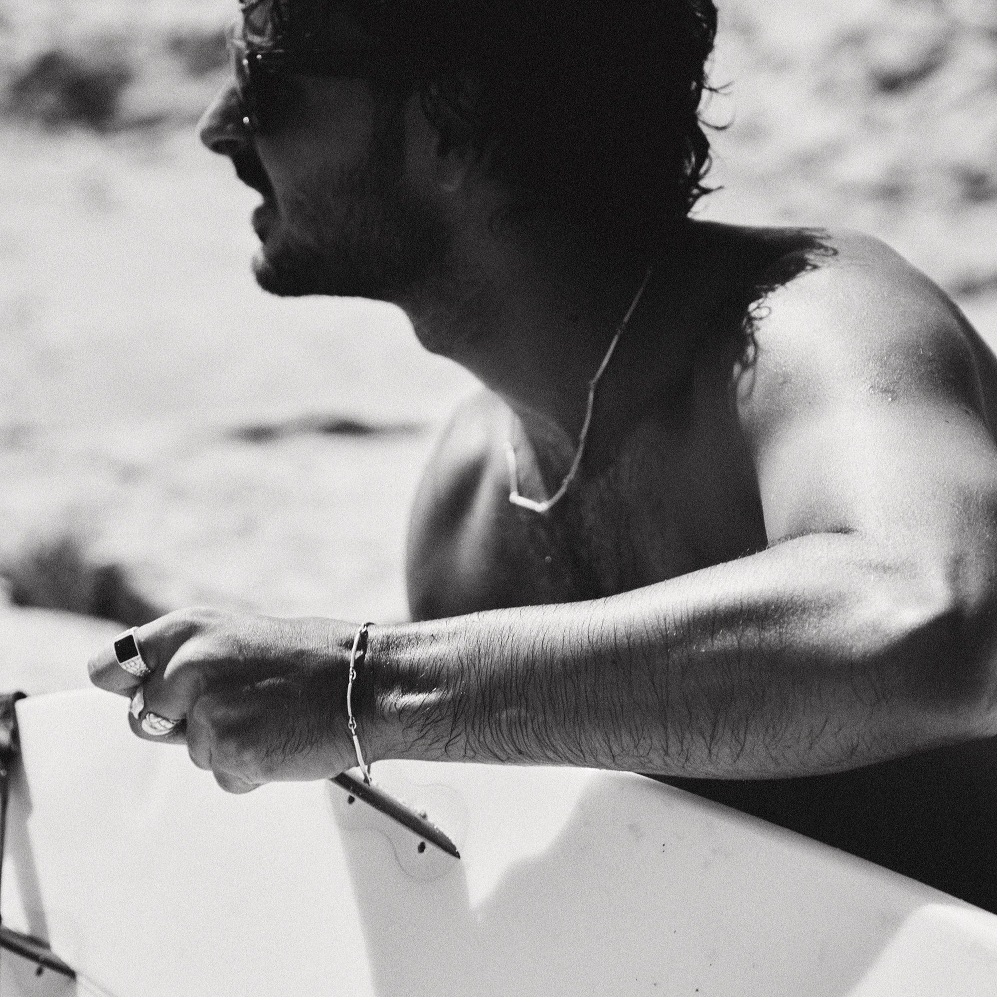 Black and white photo of a person holding a surfboard on a beach.